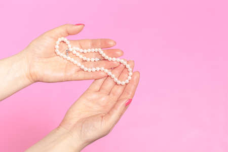 White pearl necklace on the woman's handの写真素材