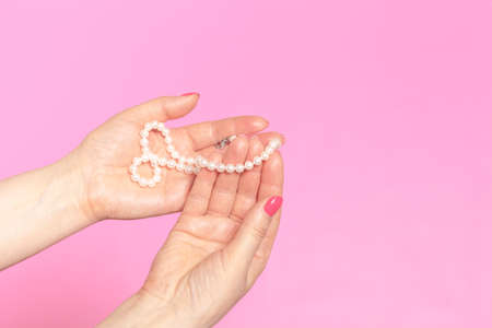 White pearl necklace on the woman's handの写真素材