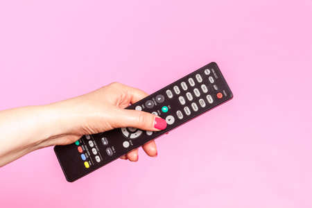 woman hand holding remote control, on pink backgroundの写真素材