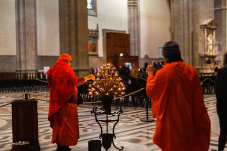 FLORENCE, ITALY â FEBRUARY 21, 2019: Buddhist monk lighting sega in the christian cathedral Duomoのeditorial素材
