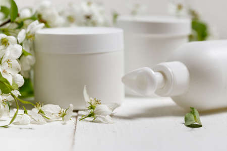 Skinâcareâ packagingââ set w/ spring flowers onâ whiteâ background.â Blank cosmetic bottle/tube of moisturizing cream w/ organic herbal ingredients. Natural beautyâ cosmetologyâ conceptの写真素材