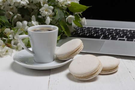 Little delicate elegant bouquet of spring flowers and a teacup on white wooden table, morning breakfastの写真素材