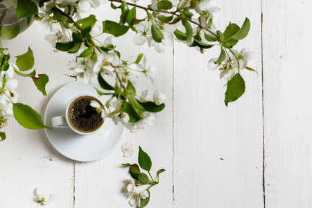 Little delicate elegant bouquet of spring flowers and a teacup on white wooden table, morning breakfastの写真素材