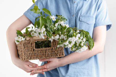 Hipster Girl in rustic linen dress holding big apple tree flowers in wicker basket on white backgroundの写真素材