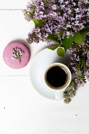 Little delicate elegant bouquet of spring flowers and a teacup on white wooden table, morning breakfastの写真素材