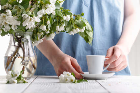 spring morning, the girl drinks coffee with a bouquet of spring flowers in a vaseの写真素材
