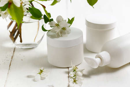Cosmetic bottle close up with white spring flowers on the white backgroundの写真素材