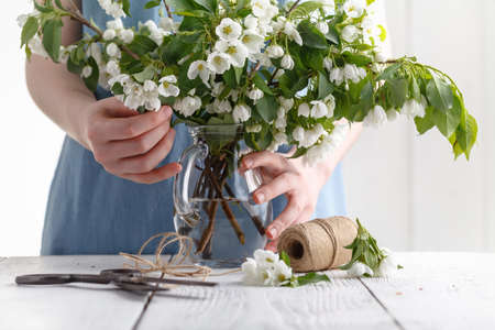 Bouquet of spring flowers in the hands of a girl on a background of blue dress. Blooming apple tree in springの写真素材