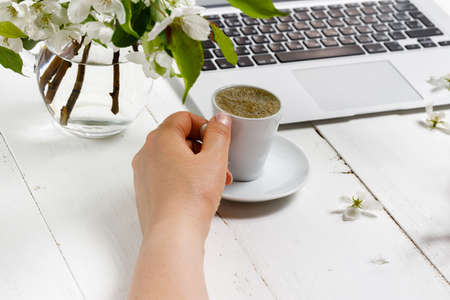 Feminine workplace concept. Freelance fashion comfortable femininity workspace  with laptop, coffee, flowers on white backgroundの写真素材