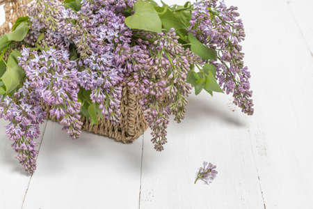 Purple lilac flowers bunch in a basket on wooden tableの写真素材