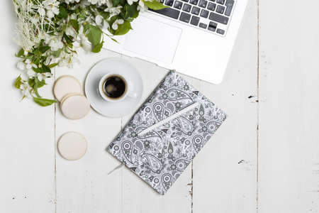 Modern feminine workplace concept. Laptop, coffee, beautiful apple tree flowers  on the white table, top viewの写真素材