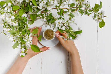 spring morning, the girl drinks coffee with a bouquet of spring flowers in a vaseの写真素材