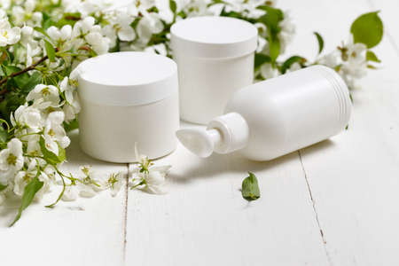 Skinâcareâ packagingââ set w/ spring flowers onâ whiteâ background.â Blank cosmetic bottle/tube of moisturizing cream w/ organic herbal ingredients. Natural beautyâ cosmetologyâ conceptの写真素材