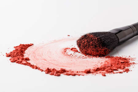 Makeup brush background with red blush sprinkled on white. Make up and female cosmetics backgroundの写真素材