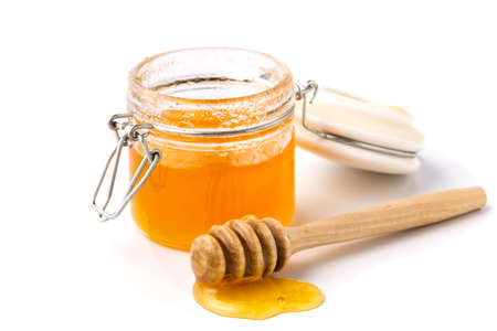 Pick up the honey jar and pour honey, isolatedの写真素材