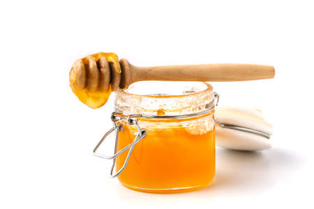 Half solid linden honey in a glass jar, isolated on whiteの写真素材