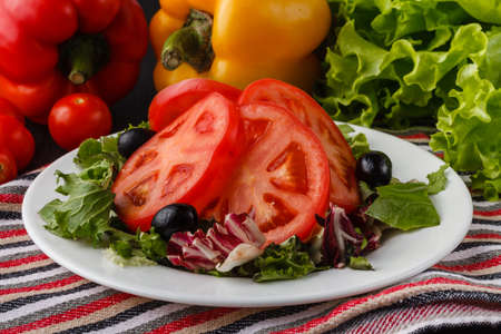 summer salad with tomatoes in white plate on wood tableの写真素材