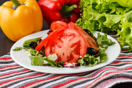 summer salad with tomatoes in white plate on wood tableの写真素材