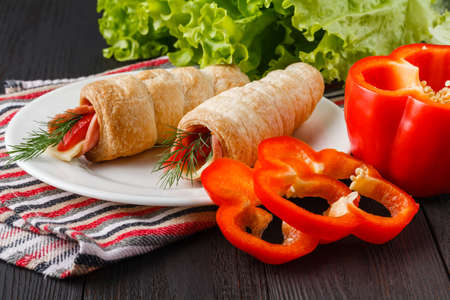 Fresh croissant with ham and salad leaf on dark wooden backgroundの写真素材