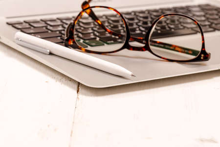 Sideview of office desk with laptop, glasses and other items