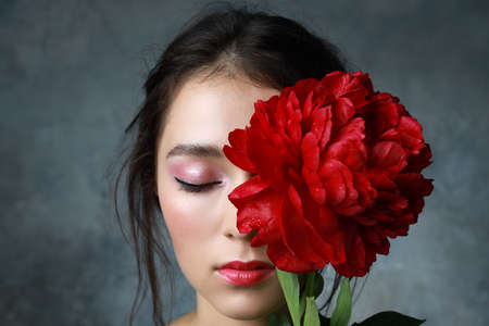 Beautiful fresh Asian woman with red peony and red lipstickの写真素材