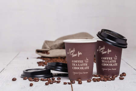 Paper cup of coffee and coffee beans on white wooden backgroundの写真素材