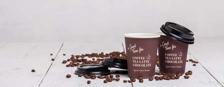 Paper cup of coffee and coffee beans on white wooden backgroundの写真素材