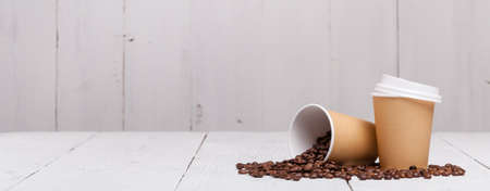 Paper cup of coffee and coffee beans on white wooden backgroundの写真素材