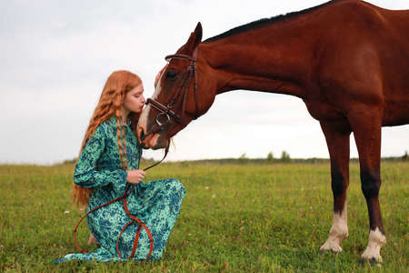 Redhead  Woman kissing her horse, autumn outdoors sceneの写真素材
