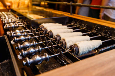 Preparation of the traditional TrdelnÃ­k a kind of spit cake made from rolled dough wrapped around a stick, grilledの写真素材