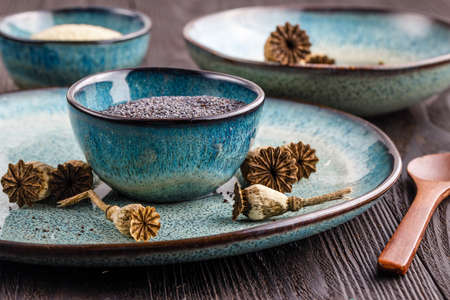 Poppy seeds and seedpods in ceramic bowlの写真素材