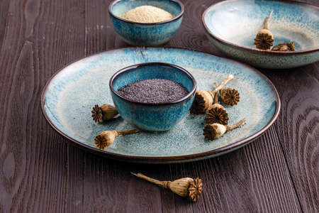 Poppy seeds and seedpods in ceramic bowlの写真素材