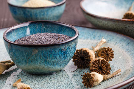 Poppy seeds and seedpods in ceramic bowlの写真素材