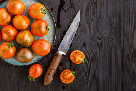 half and whole tomatoes on brown textured woodの写真素材