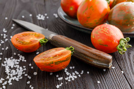 fresh whole cherry tomatoes and slices scattered on a black boardの写真素材