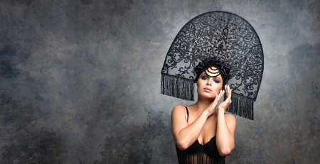 beautiful young girl in lace bodysuit and fashionable kokoshnik on a background of gray wallの写真素材