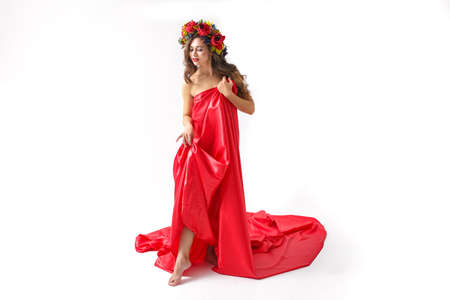 Beauty portrait of a young woman with a wreath of red roses on her headの写真素材
