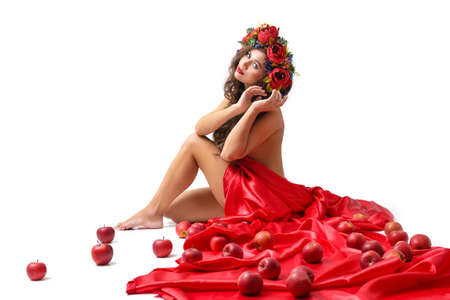Beautiful woman with flowers in her red hair she is lying relaxed on whiteの写真素材