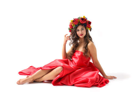 Beauty portrait of a young woman with a wreath of red roses on her headの写真素材