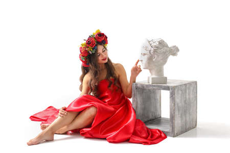 Beautiful romantic young woman in a wreath of flowers posingの写真素材