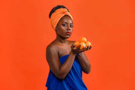Tender african american young woman holding and smelling fresh fruitsの写真素材