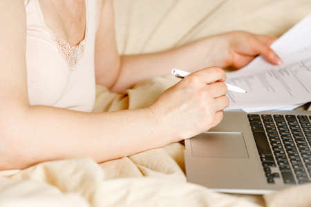 Woman employee in bed with laptop computer in self isolation working from home, coronavirus covid-19 quarantine. Remote working of business worker, online education. Prevention of virus spreadの写真素材