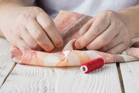 hands sewing fabric with needle at seamstress workplaceの写真素材