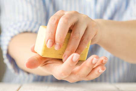Women hands are holding soap. Soap foam on the hands. Yellow soap. Woman washes soap with hands  Virus protection. COVID-19の写真素材