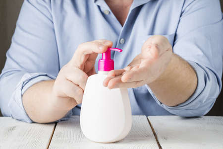 hands using wash hand sanitizer gel pump dispenser. Clear sanitizer in pump bottle, for killing...