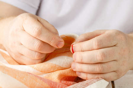 hands sewing fabric with needle at seamstress workplaceの写真素材