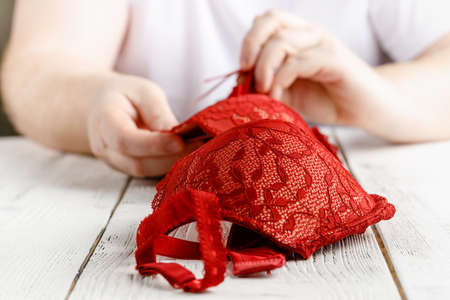 Men hold red sexy female bra and looking on it, bayer concept