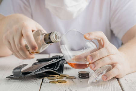 Alcohol addicted man at the table. Sad depressed male adult in quarantineの写真素材