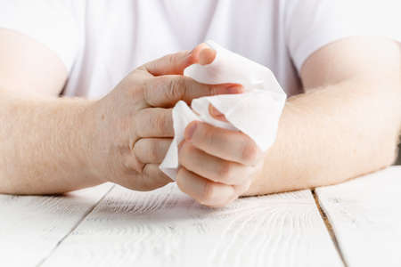 Close up on midsection of man hands wiping using white alcohol tissue cleaning napkin disinfection from virus and bacteria in day at home or officeの写真素材