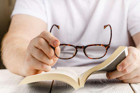 Reading book close up view in hands with glassesの写真素材